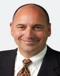 A person in a suit smiling

Description automatically generated