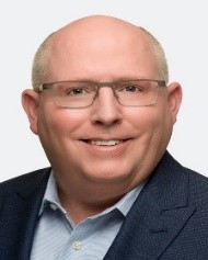 A person wearing glasses and a suit

Description automatically generated