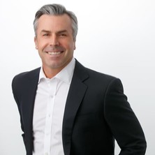 A person in a suit smiling  Description automatically generated with low confidence