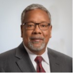 A person wearing glasses and a suit  Description automatically generated with medium confidence